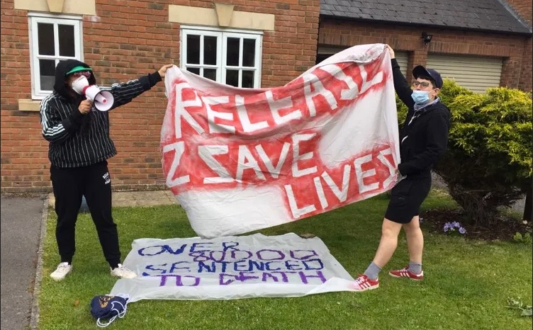 Picture shows two people holding a banner saying 'release 2 save lives'