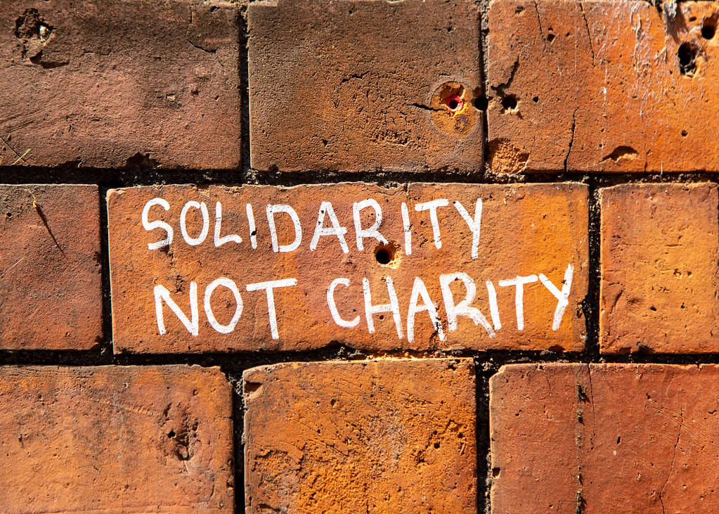 Image shows solidarity not charity sprayed on a brick wall