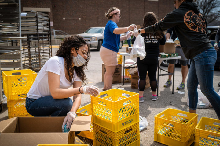 Image shows a group of people packing supplies into yellow crates
