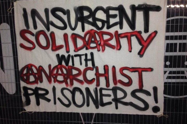 Image is a banner saying insurgent solidarity with anarchist prisoners