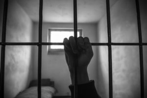 Image shows a raised fist holding cell bars