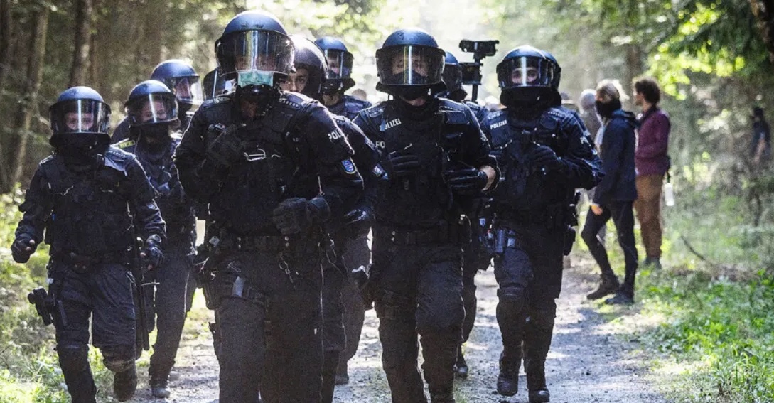 Image shows a group of police running in a forest