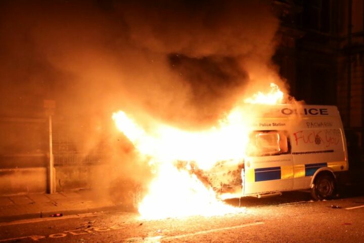 Image shows a police riot van burning